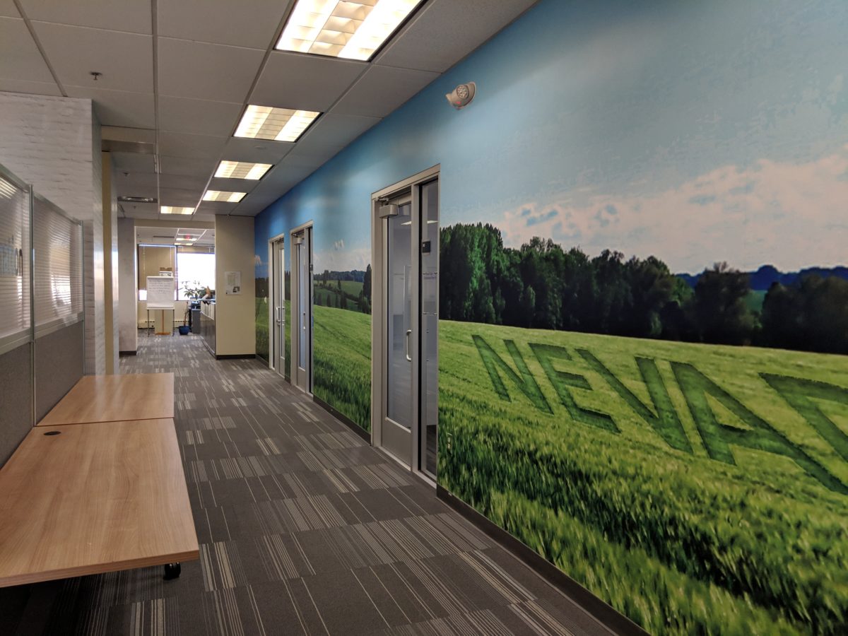 Hallway with two tables on the left. On the wall on the right is a big grass field and sky decal with "NEVA" from Nevada visible.
